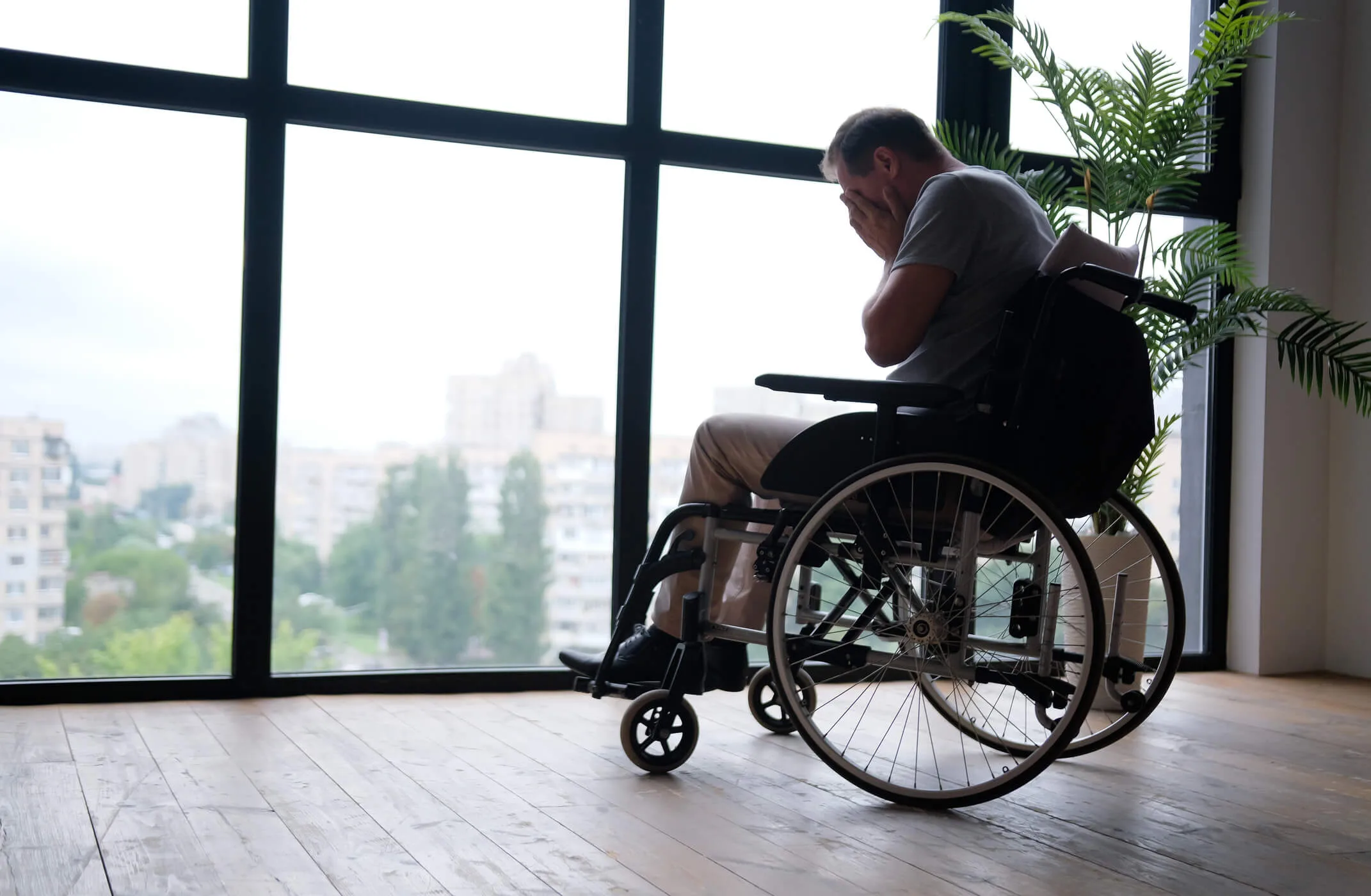 Elderly man in wheelchair crying near window indoors