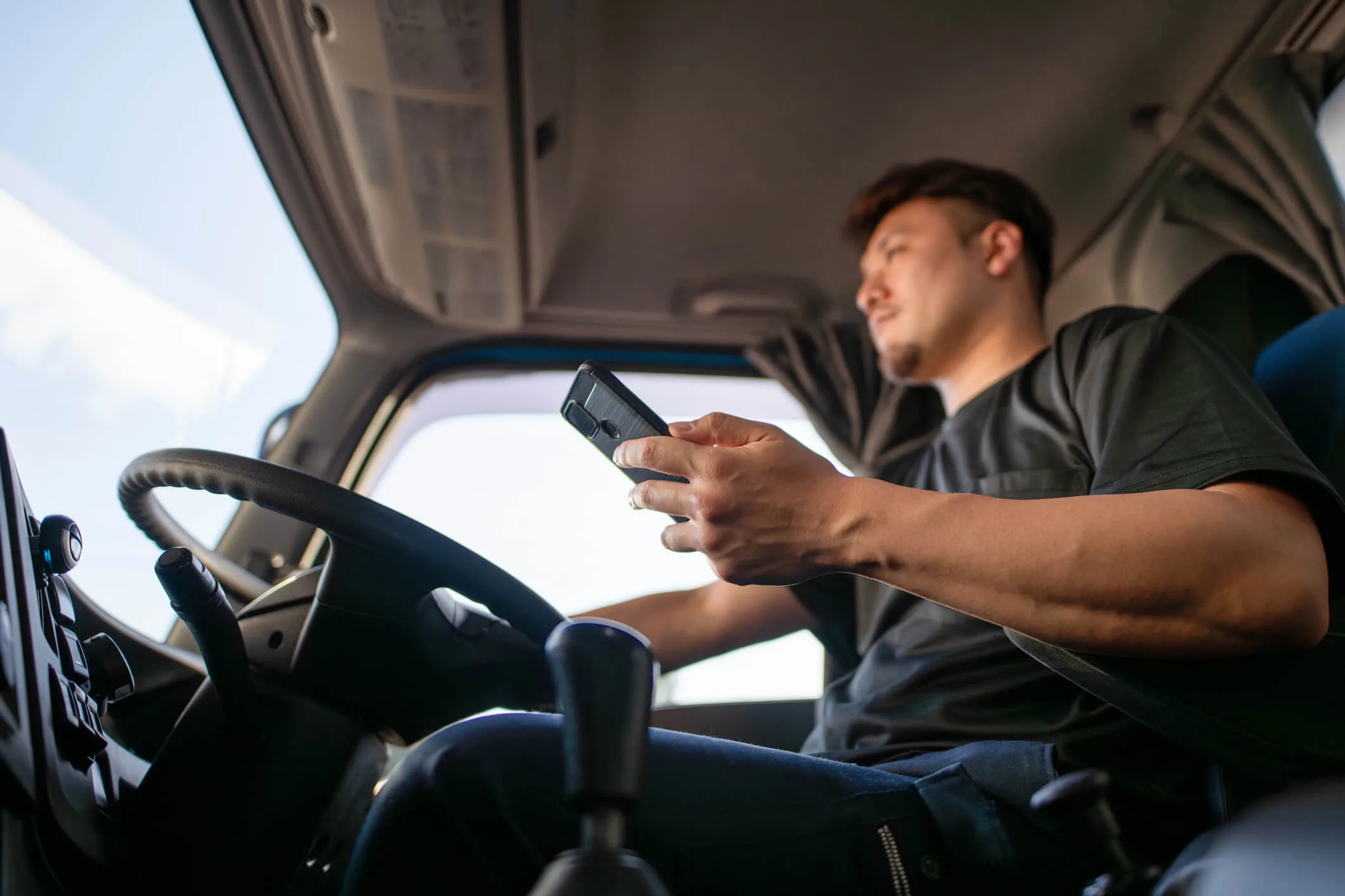 Truck driver driving while looking at smartphone
