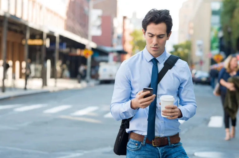 Young man text messaging through cell phone while walking on the road