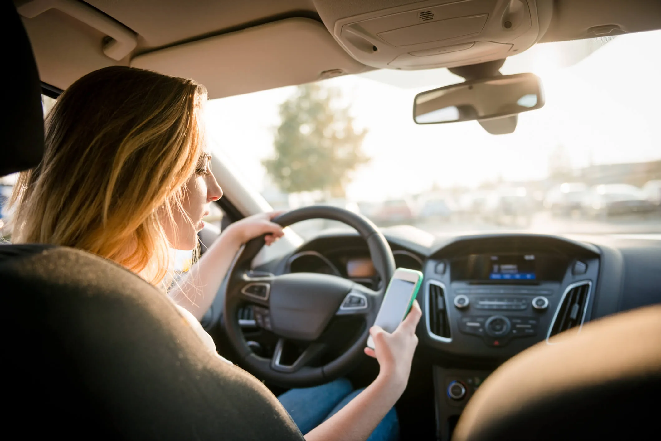 teen driver looking to her smartphone while driving car