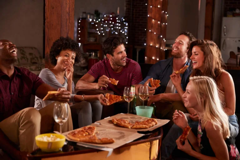 Young adults sharing pizzas at a party at home