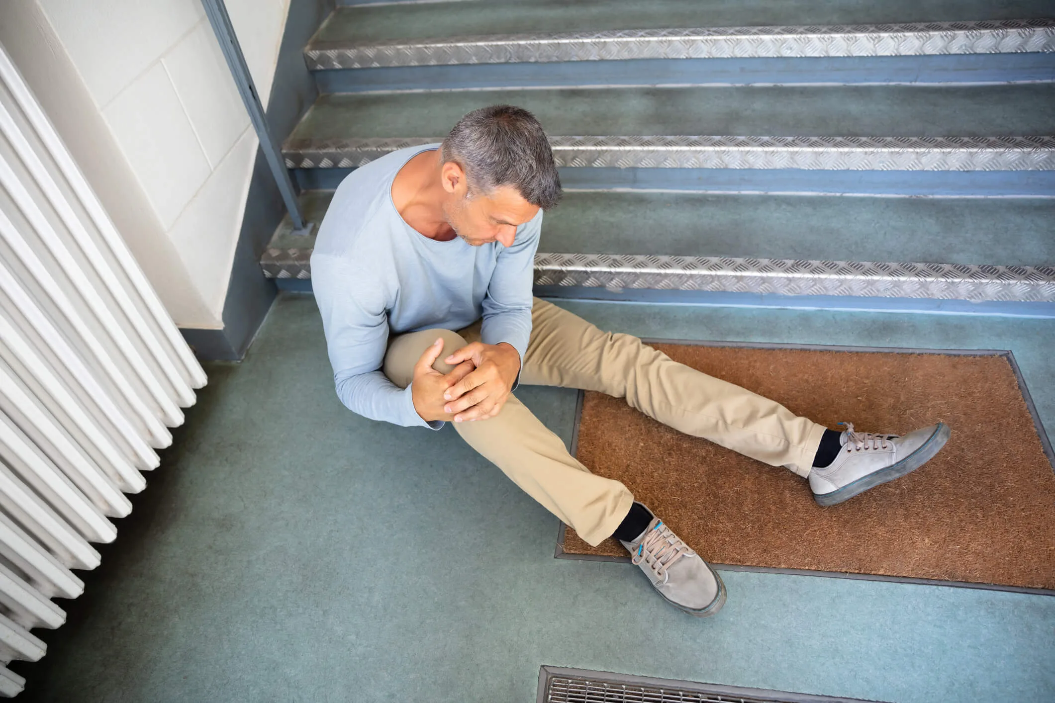 Mature Man Sitting On Staircase After Slip And Fall Accident