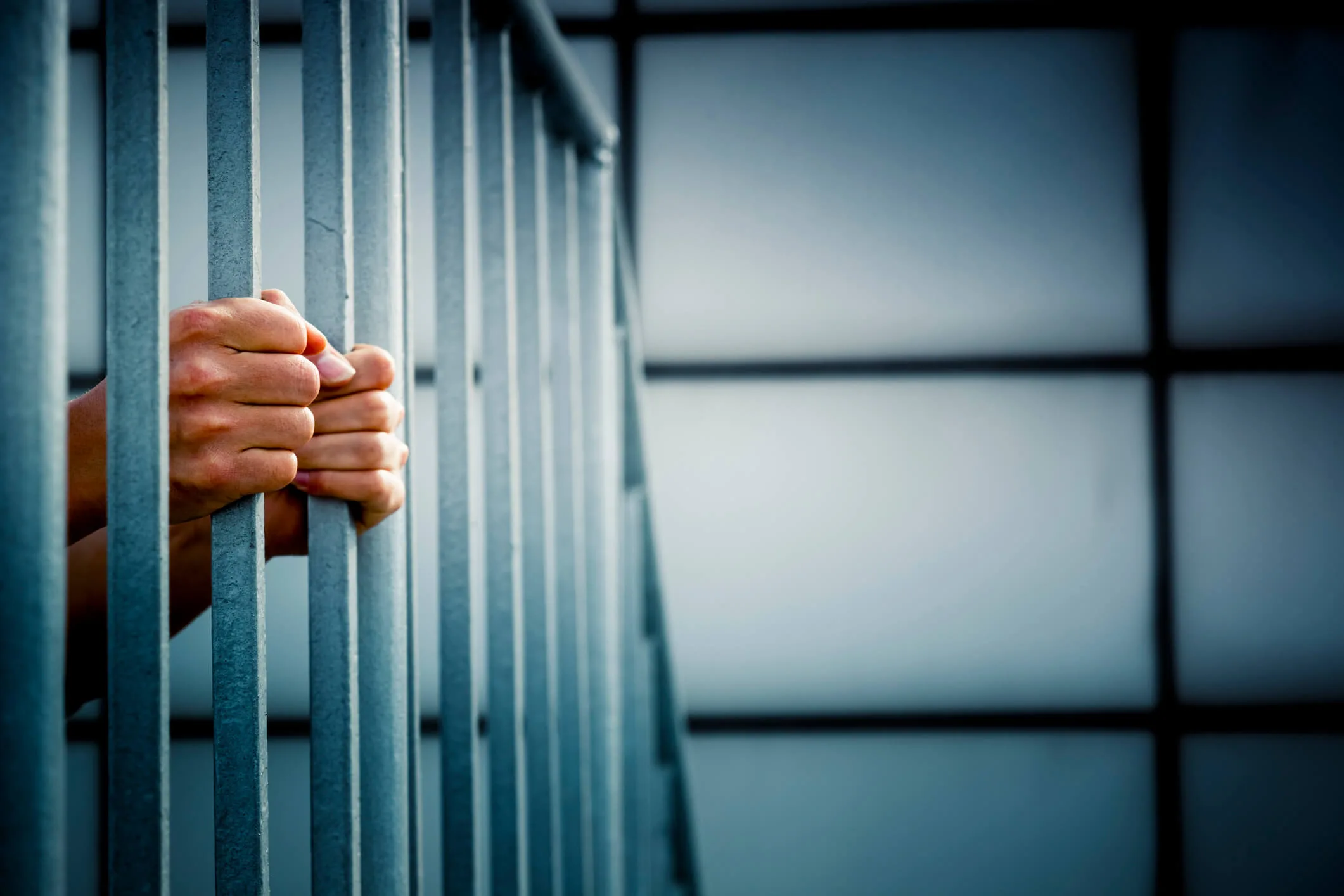 A prisoner behind the jail cell bars.
